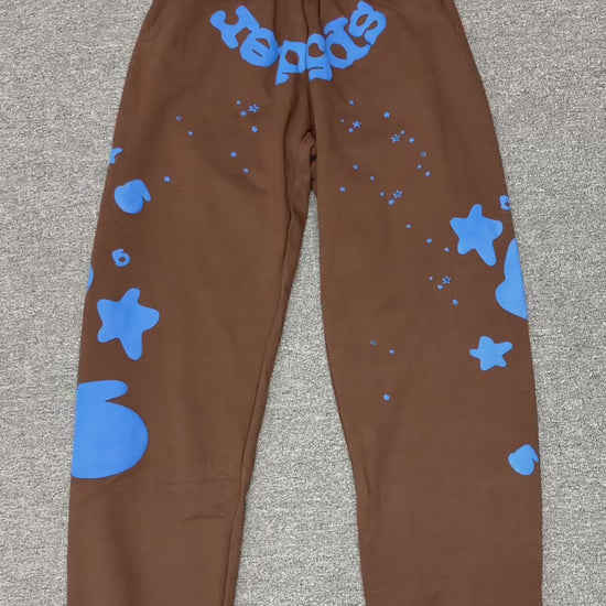 SP5DER Beluga V2 brown sweatpants front view with blue logo and oversized star graphics