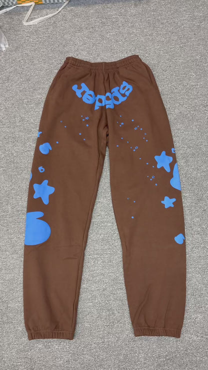 SP5DER Beluga V2 brown sweatpants front view with blue logo and oversized star graphics