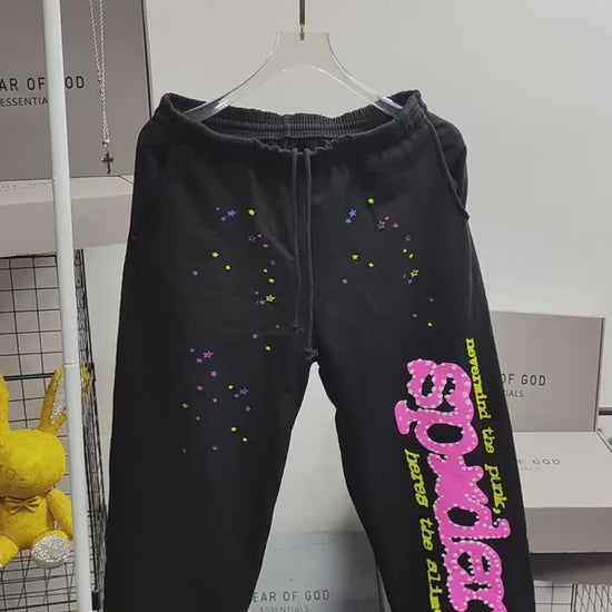 Sp5der P*NK sweatpants black front view with pink rhinestone logo and multicolor star graphics