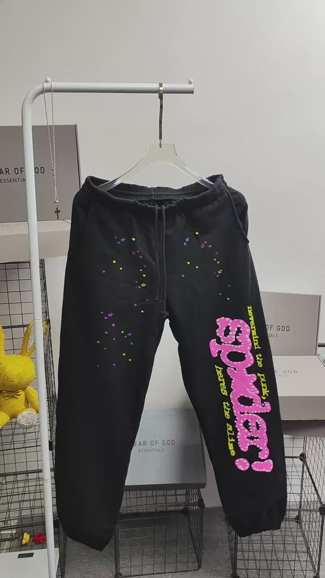 Sp5der P*NK sweatpants black front view with pink rhinestone logo and multicolor star graphics